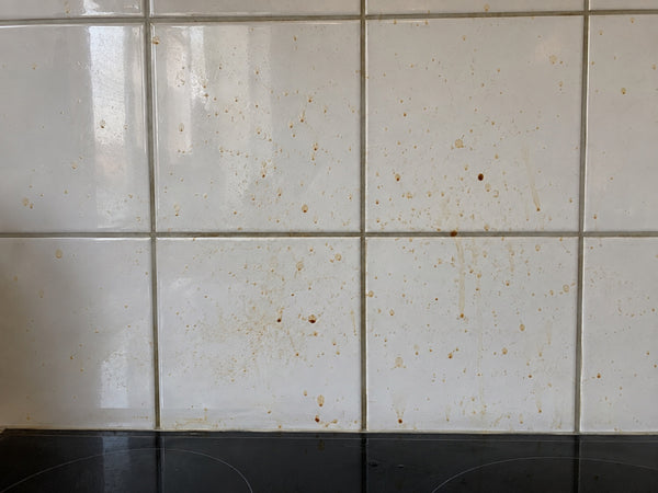 Tegelwand met vetvlekken achter een kookplaat